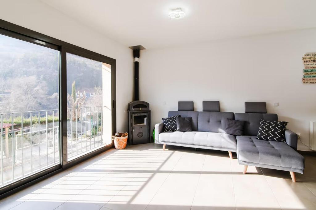 a living room with a couch and a large window at La Caseta de Cercs, Barbecue y Pet Friendly in Sant Jordi de Cercs