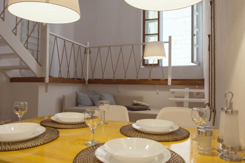 a dining room with a table with plates and wine glasses at Alleyway House in Hydra