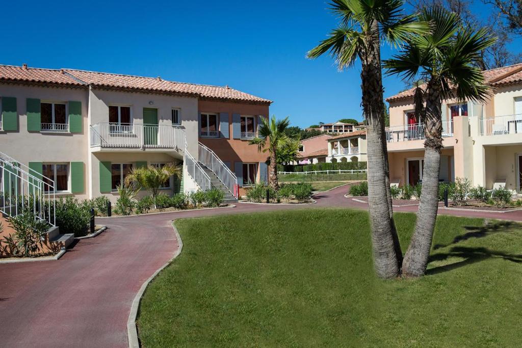 une passerelle devant un bâtiment planté de palmiers dans l'établissement SOWELL RESIDENCES Les Perles de Saint Tropez, à Grimaud