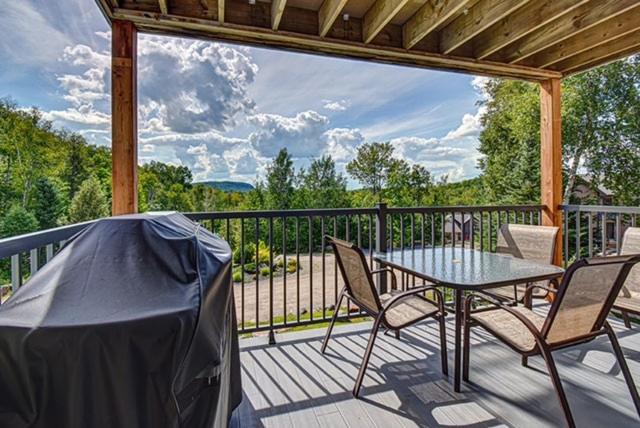 a patio with a table and chairs on a deck at Le Zénitude Mont-Blanc in Saint-Faustin