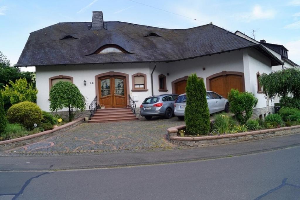 a white house with cars parked in front of it at Pension Birgit Pazen in Zeltingen-Rachtig