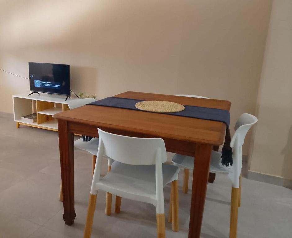 a wooden table with white chairs and a television at Parador de Chacras Suite in Ciudad Lujan de Cuyo