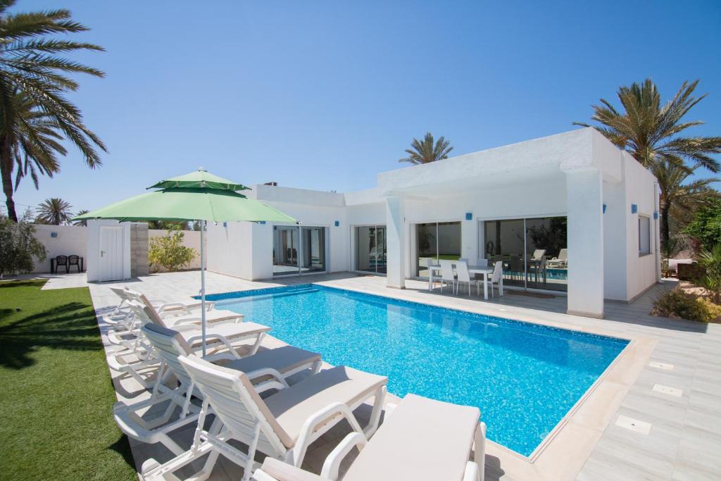 een villa met een zwembad, stoelen en een parasol bij Villa Dar Salama, 3 Chambres, Plage à 5 minutes in Midoun