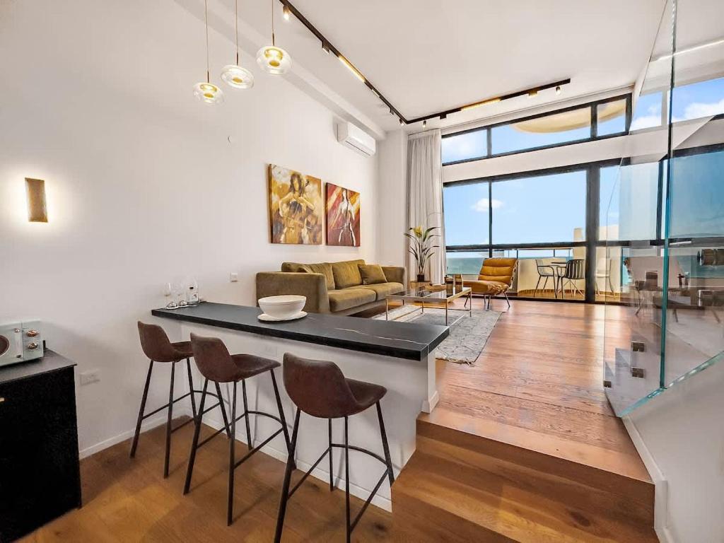 Herzliya PituahにあるBeachfront Sky Loftのキッチン、リビングルーム(カウンター、椅子付)