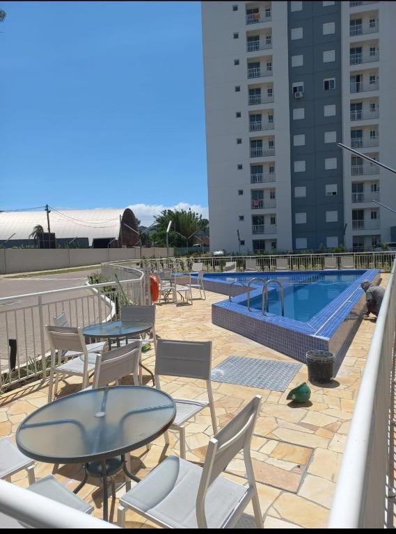 a patio with tables and chairs next to a swimming pool at Apartamento Solar dos Pampas in Guaíba