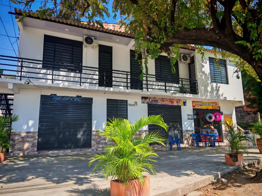 a white building with black garage doors and palm trees at Air b&b altos del peñon in Girardot