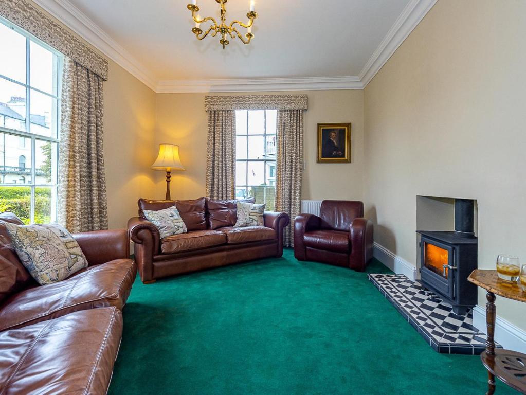a living room with leather furniture and a fireplace at Langford Villa in Filey