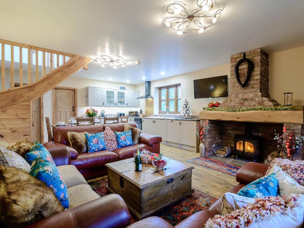 a living room with leather furniture and a fireplace at Farriers Lodge in Burshill