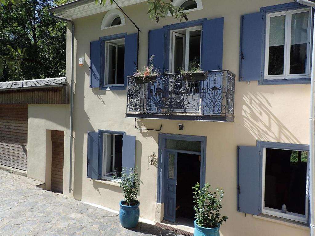 a building with blue shutters and a balcony at Cottage by River with Spa near Carcassonne in Caudebronde