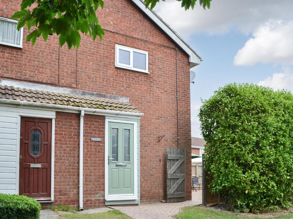 a red brick house with a green door at Corner House in Sewerby