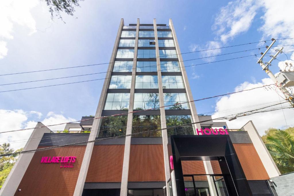ein hohes Gebäude mit einem rosa Schild darauf in der Unterkunft Edificio Village Lofts - Ao lado da Vila Germânica in Blumenau