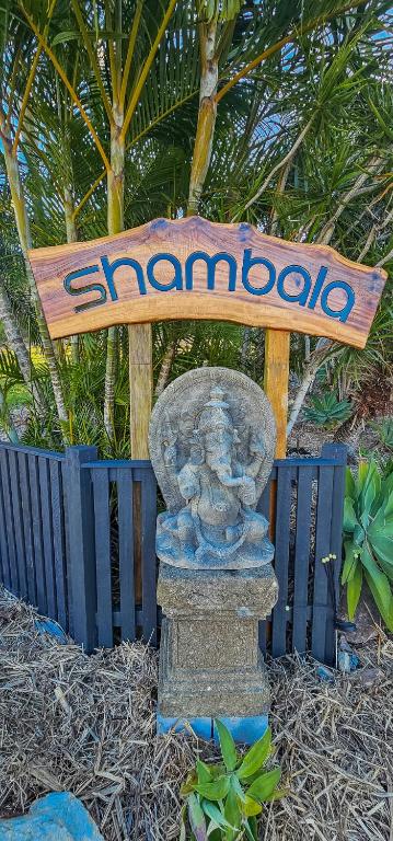 a sign with a statue in front of a fence at Shambala Pet Friendly Apartments Agnes Water in Agnes Water