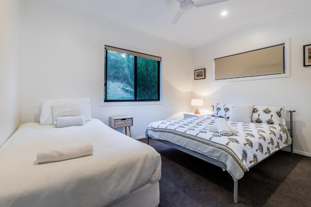 twee bedden in een kamer met witte muren bij Shambala Pet Friendly Apartments Agnes Water in Agnes Water