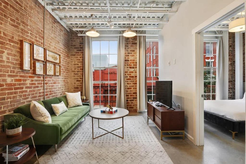 a living room with a green couch and a bed at Modern One Bedroom with Balcony in New Orleans