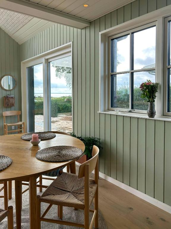 a dining room with a table and chairs and windows at Holiday Home With Sea View Near Hesselager in Hesselager