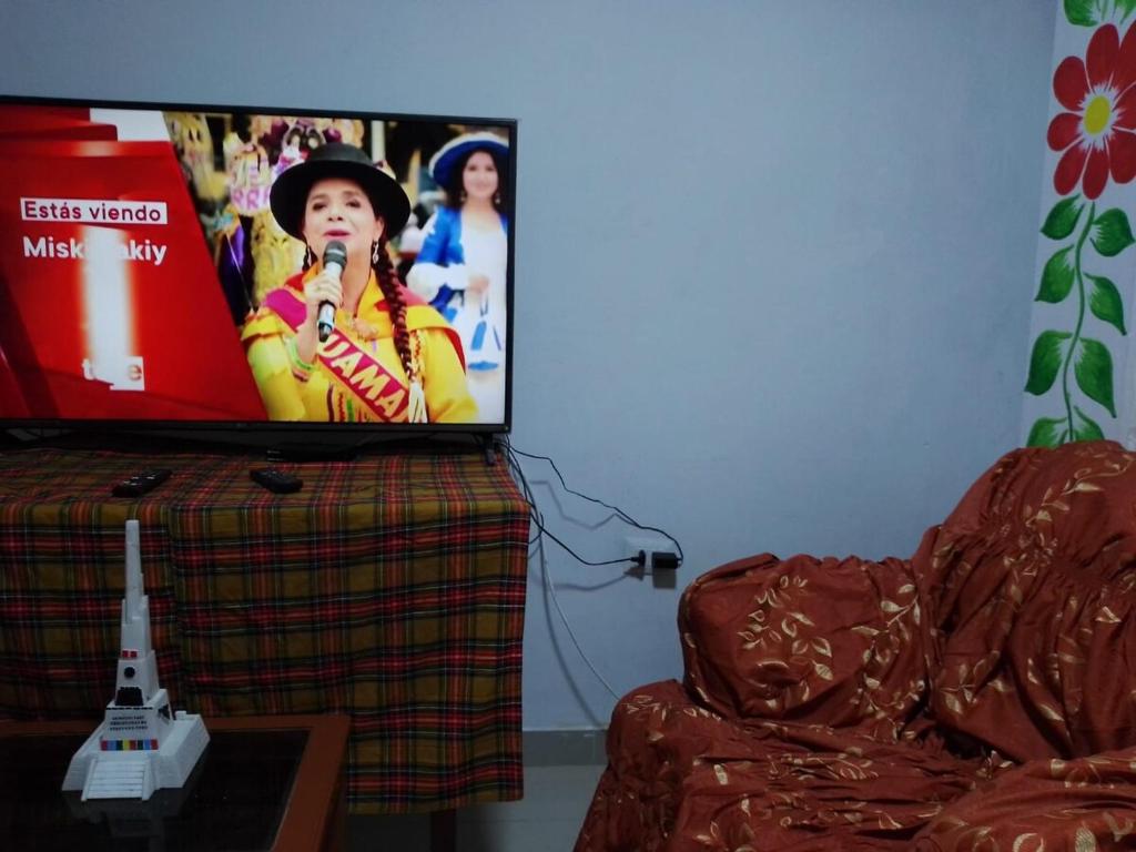 una pantalla de TV con una mujer cantando en un micrófono en Condominio Las Torres, en Ayacucho