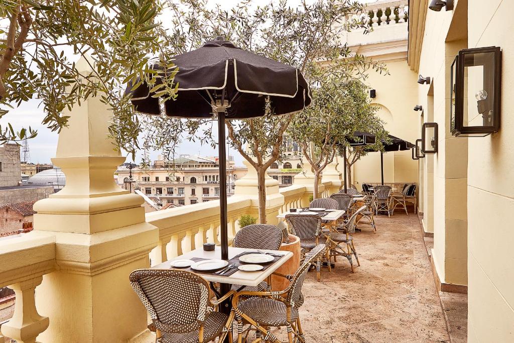 a balcony with tables and chairs and an umbrella at The Principal Madrid, Small Luxury Hotels in Madrid