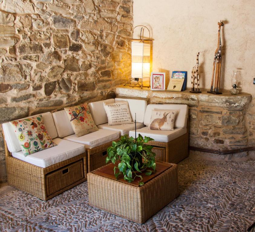 a living room with couches and a stone wall at Hotel Rural Casa Indie in Rabanal del Camino