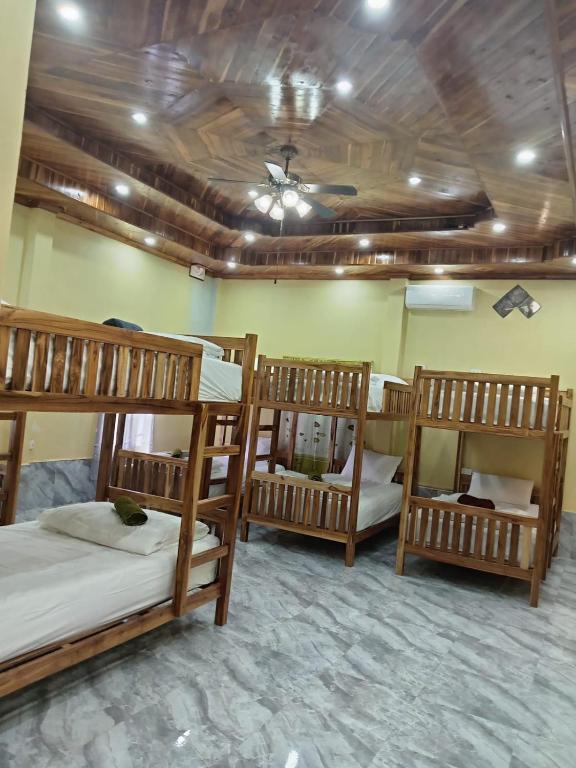 three bunk beds in a room with a ceiling at Sunset Backpackers Hostel in Nongkhiaw
