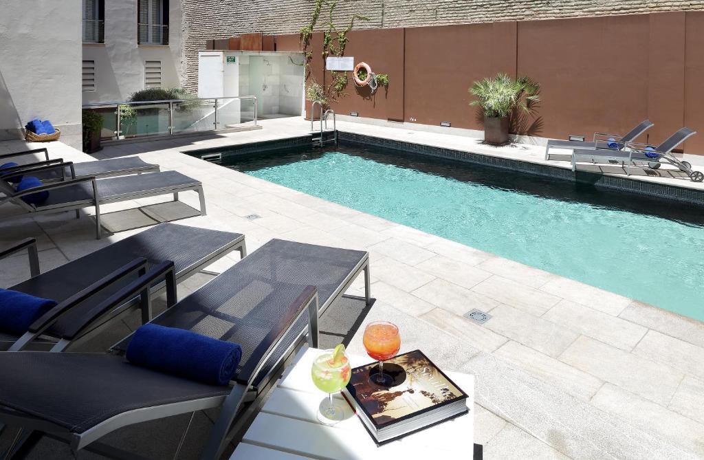 a pool with tables and chairs next to a building at Eurostars Sevilla Boutique in Seville