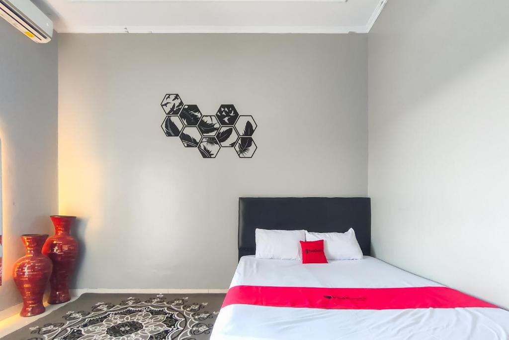 une chambre avec un lit avec un oreiller rouge et une horloge dans l'établissement RedDoorz at NN Guest House Exit Tol Klodran Solo, à Solo