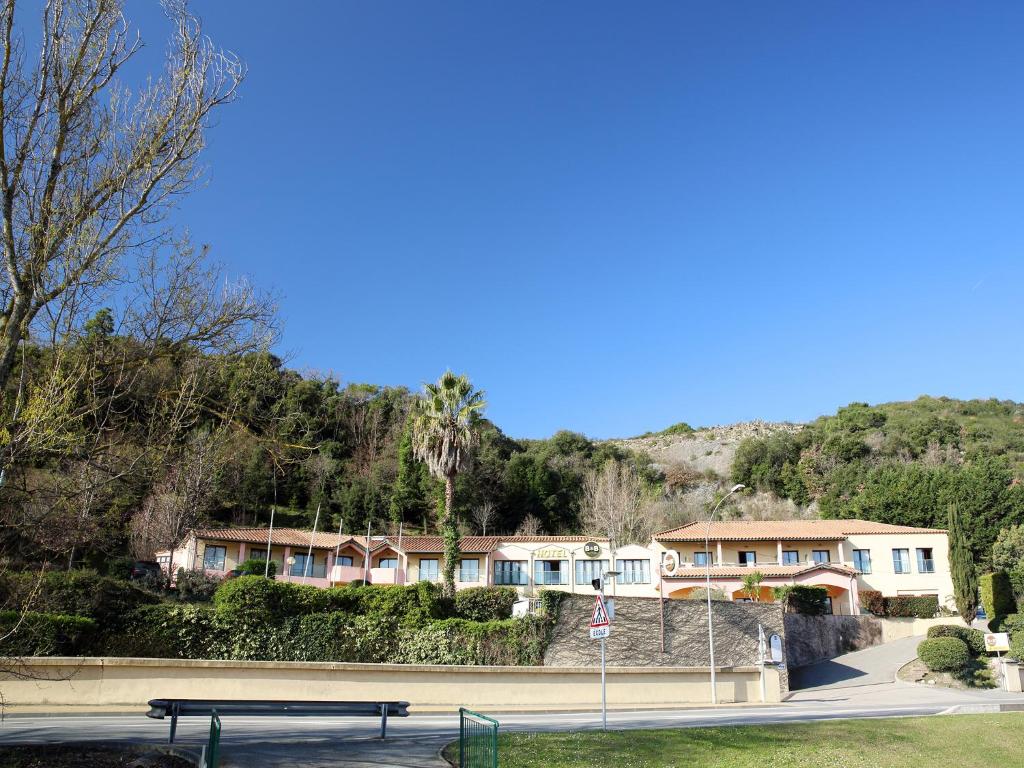 a park with a bench in front of a house at B&B HOTEL Villeneuve Loubet Village in Villeneuve-Loubet