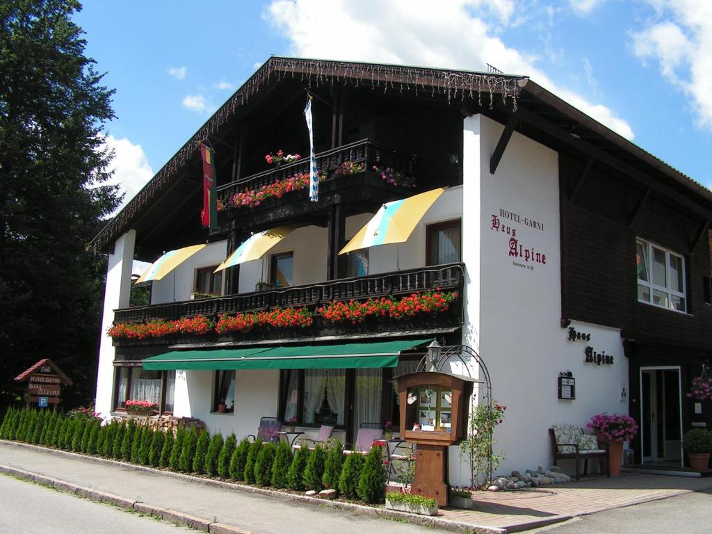 a black and white building with flowers on the balconies at Hotel Garni Haus Alpine - Chiemgau Karte inkl in Ruhpolding