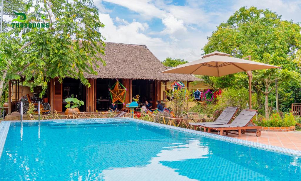 a swimming pool with chairs and an umbrella at Homestay Thùy Dương 2 in Cai Be