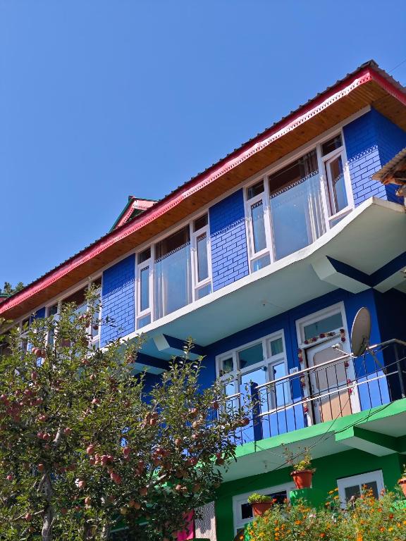 a blue building with windows and a balcony at The District Green in Kalpa