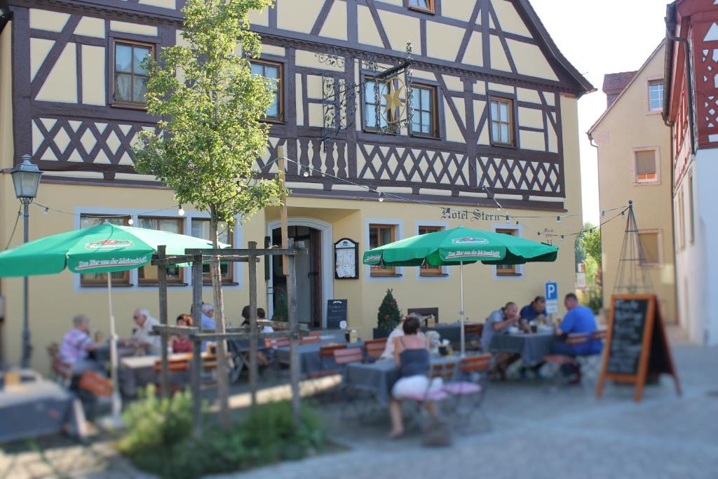un grupo de personas sentadas en mesas frente a un edificio en Hotel-Restaurant Stern, en Geiselwind