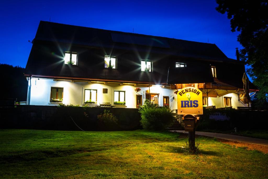 a house with a sign in front of it at night at Penzion Iris Krkonoše in Horní Maršov