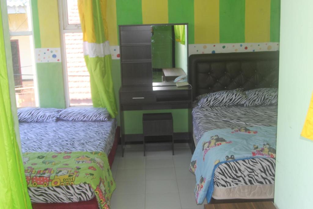 a bedroom with two beds and a mirror and a desk at De'Vita Family Homestay in Malang