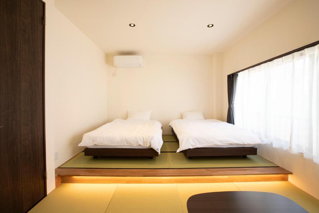 two beds in a room with a window at RouTe5 in Matsumoto