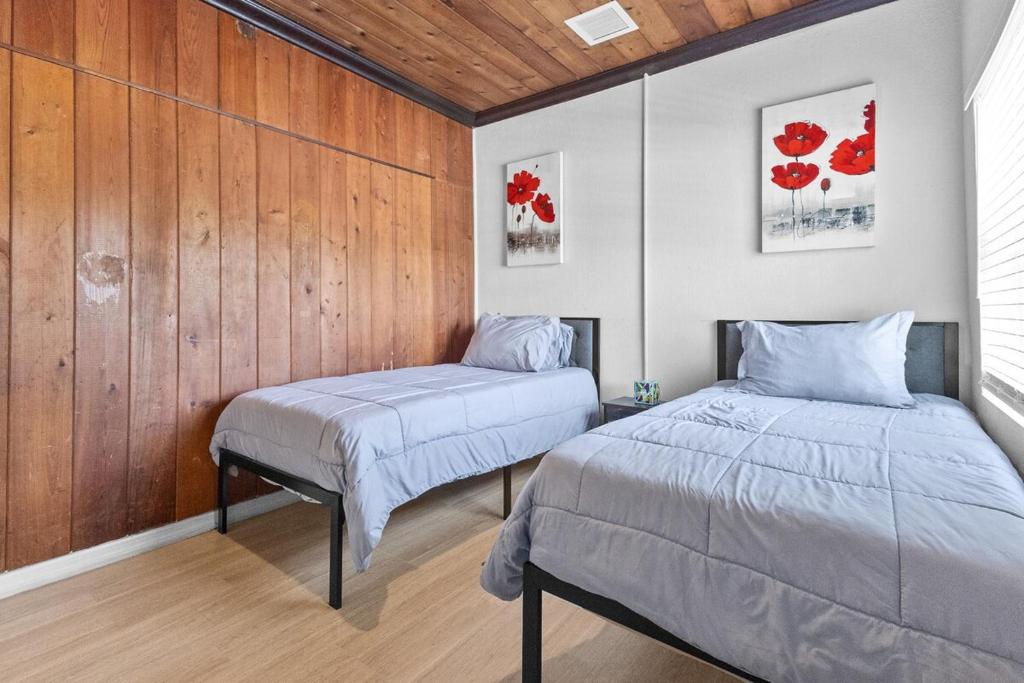two beds in a room with wood paneled walls at 4 Bedroom Modern Luxe Retreat with Hot Tub 5 Mins to Beach in West Palm Beach