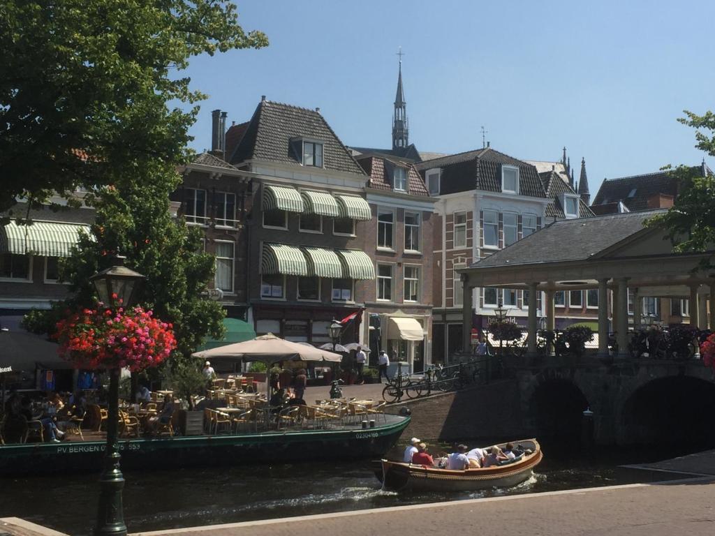 een groep mensen in boten op een rivier met gebouwen bij NR22 Leiden in Leiden