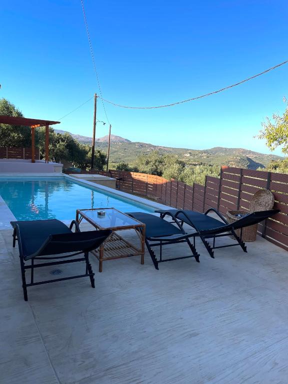 a pool with two chairs and a table next to it at Wild Tulip Escape in Kolymvari