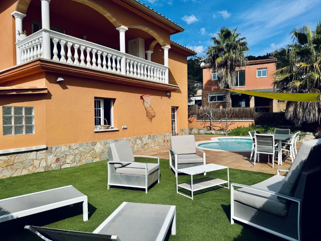 un cortile con sedie, una piscina e una casa di Hauzify I Casa Sa Calma a Platja  d'Aro
