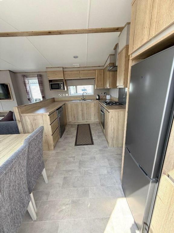 a kitchen with wooden cabinets and a stainless steel refrigerator at Rockley Park - Holiday Accommodation 22180 in Lytchett Minster