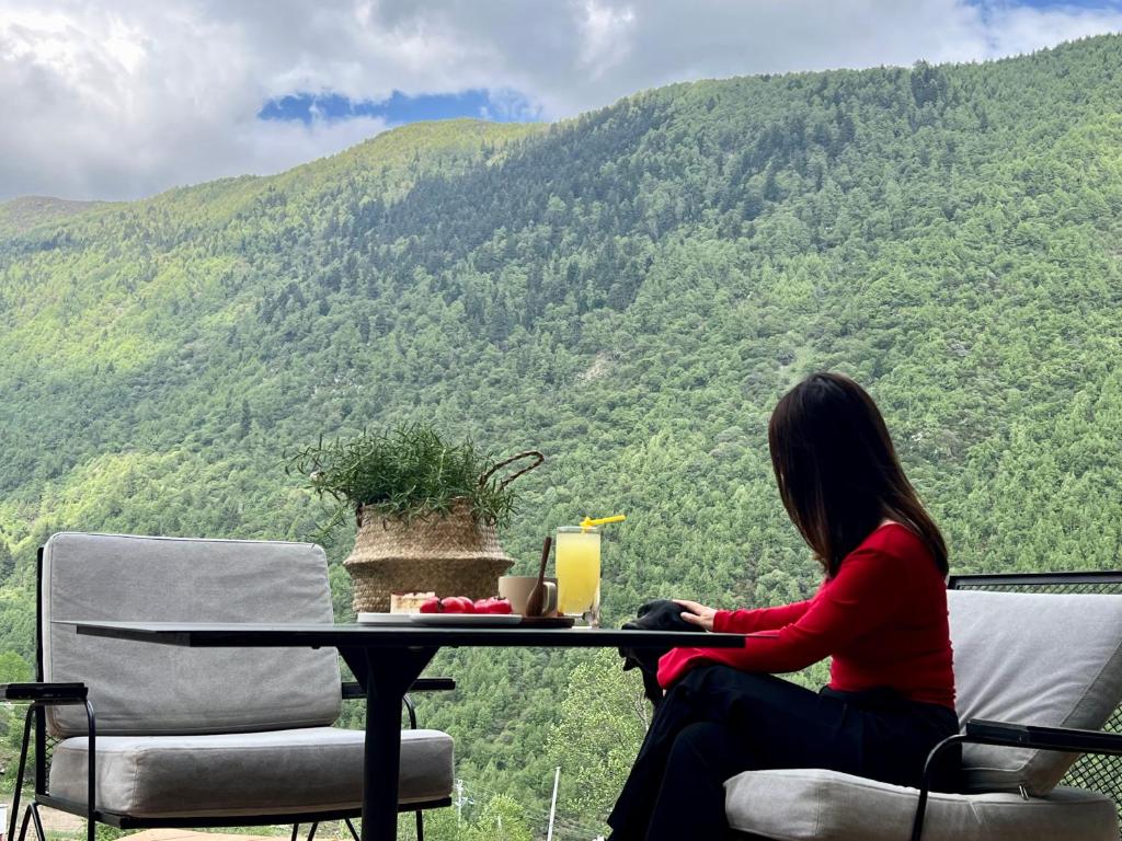 a woman sitting at a table with a view of a mountain at Mid Hill White Lodge in Mount Siguniang