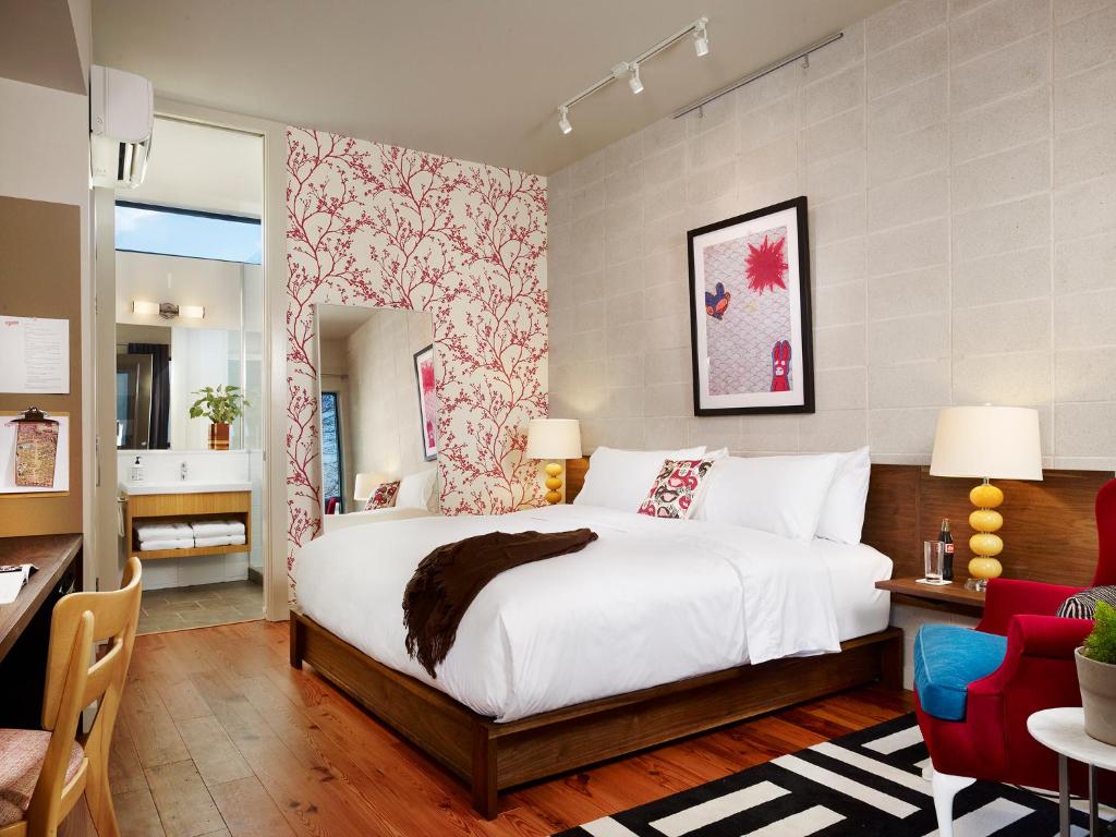 1 dormitorio con cama blanca y pared roja y blanca en Heywood Hotel, en Austin