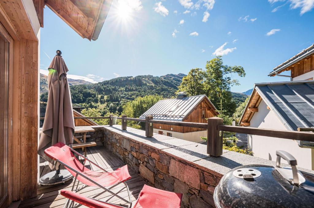a balcony with chairs and an umbrella on a building at Lune des Alpes - Chalet de charme in Valloire