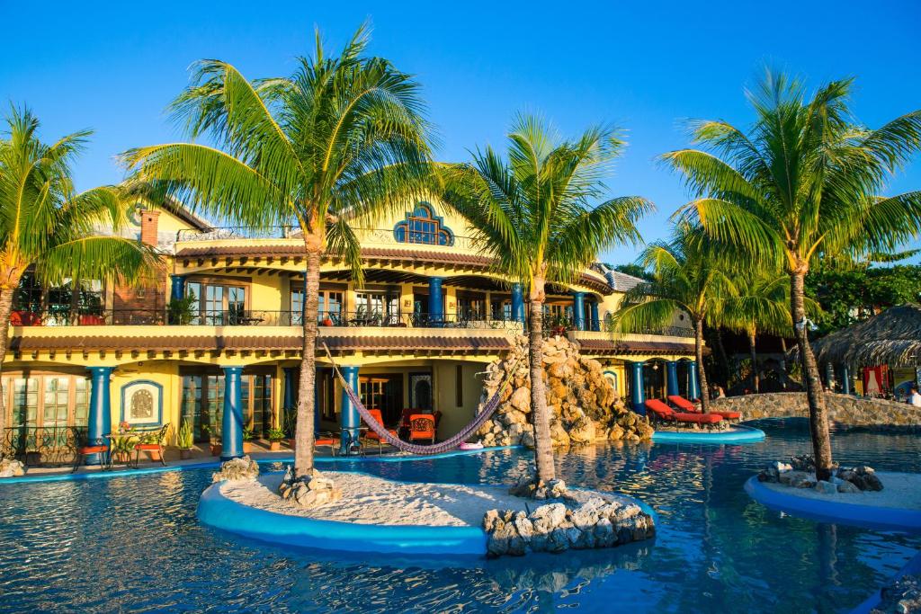 a resort with a slide in the water with palm trees at Caribe Tesoro in West Bay