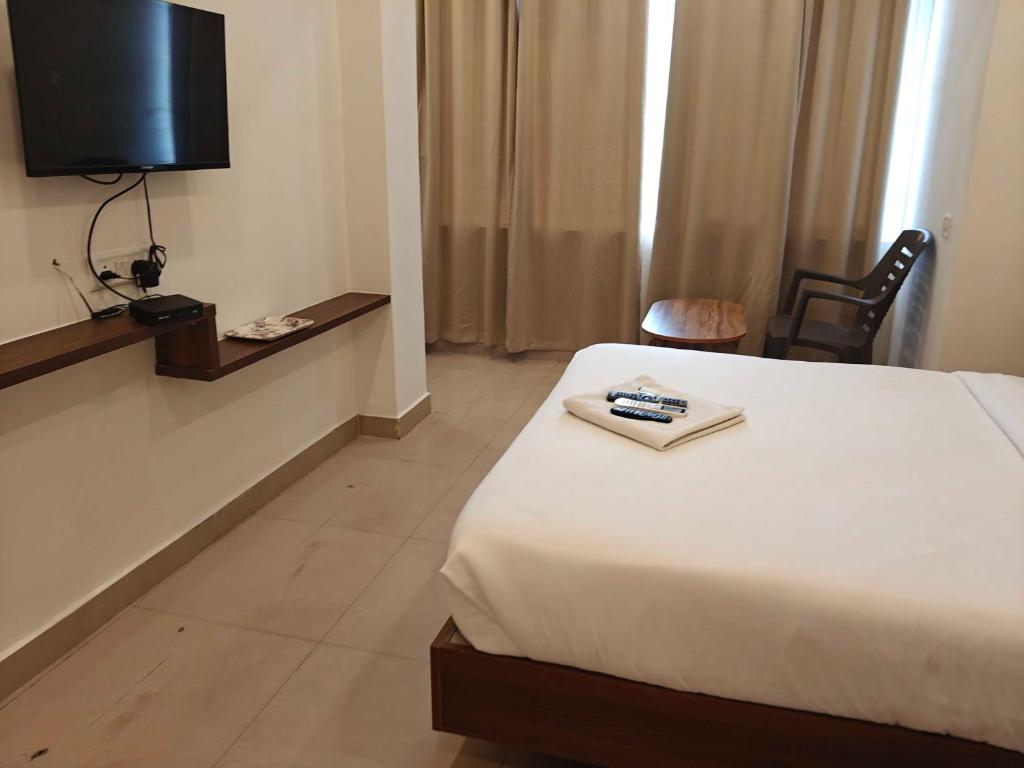 a hotel room with a bed and a television at Temple View Residency in Tiruvallūr
