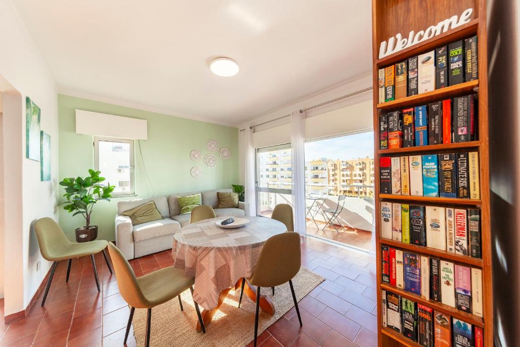 uma sala de estar com uma mesa e uma estante cheia de livros em Praia da Rocha Beach Step em Portimão
