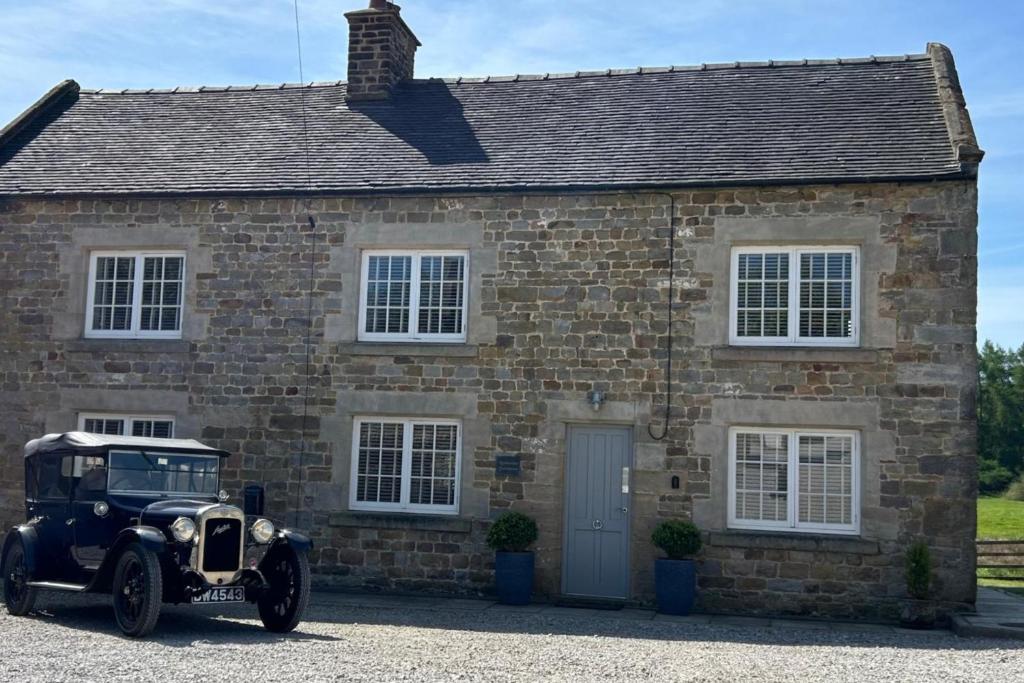 an old car parked in front of a brick house at Stunning 4 Bed Peak Dist Farmhouse Alton Towers in Waterfall