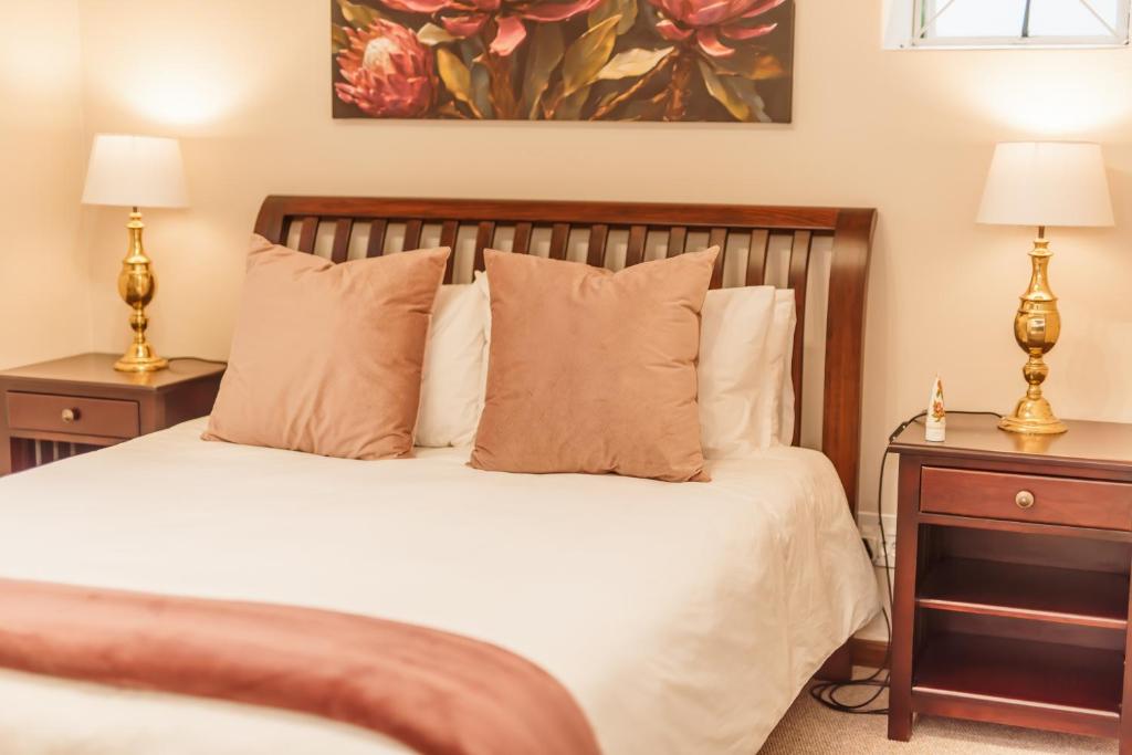 een slaapkamer met een wit bed en 2 nachtkastjes bij Protea Garden Cottage in Stellenbosch