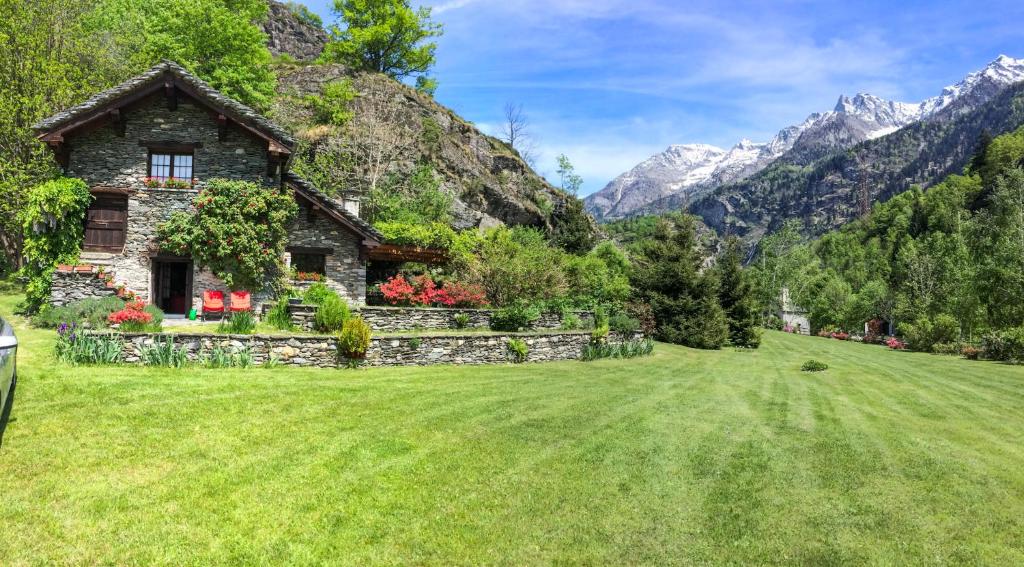 a house in a field with mountains in the background at Chalet La Baita in Baceno