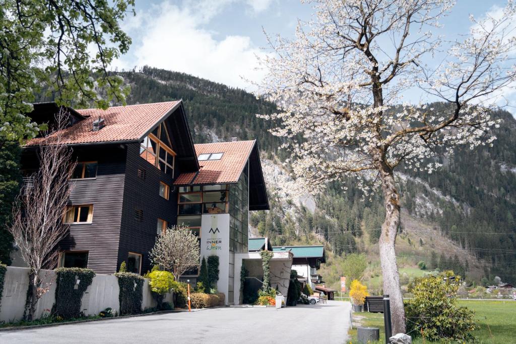 a building with a tree in front of a mountain at Apart-Garni Innerwiesn in Mayrhofen