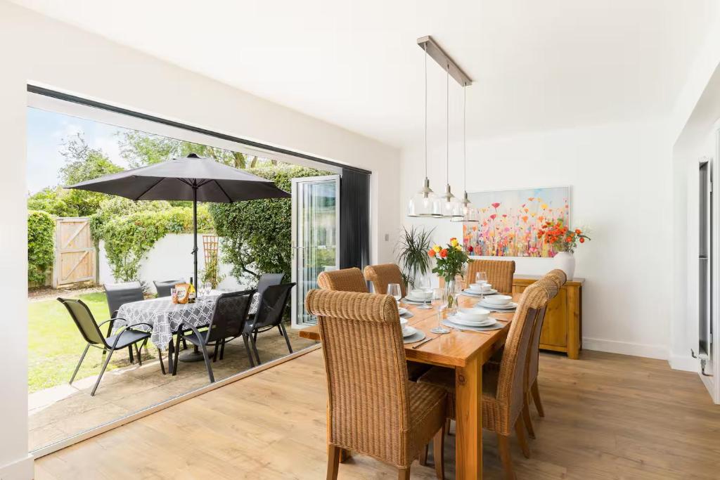 a dining room with a table and chairs and an umbrella at Pass the Keys Modern family home Garden Parking in Bourton on the Water