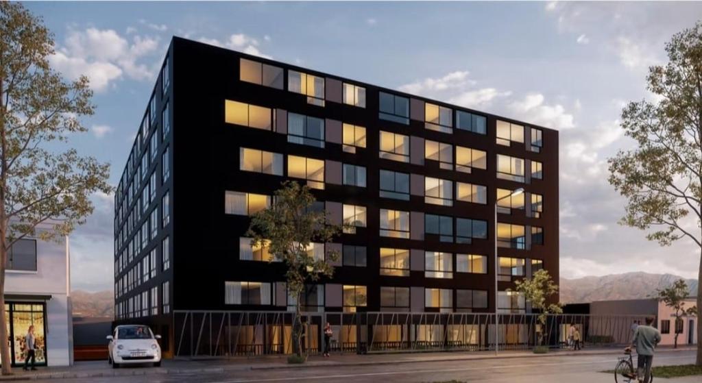 Un edificio negro con un coche delante. en Movistar Arena - Ohiggins Park - Parking, en Santiago